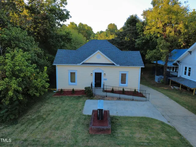 a front view of a house with a garden and trees