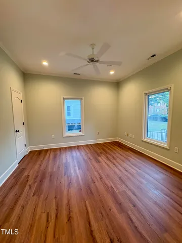 an empty room with wooden floor and windows