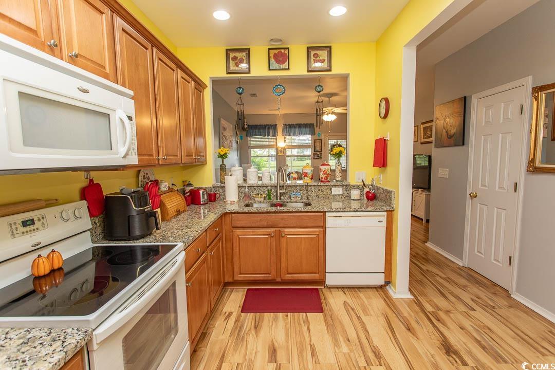 328 Kiskadee Loop, Unit E Conway, SC 29526 - Photo 7 of 37 Kitchen featuring white appliances, light stone countertops, light wood finished floors, brown cabinets, and recessed lighting