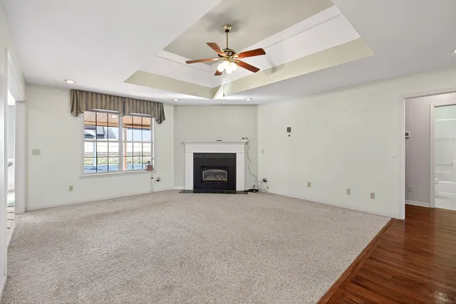 an empty room with chandelier fan and windows