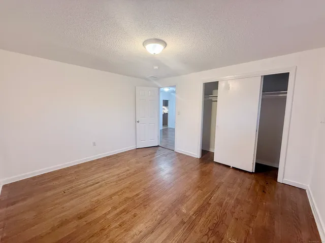 a view of an empty room with wooden floor and closet