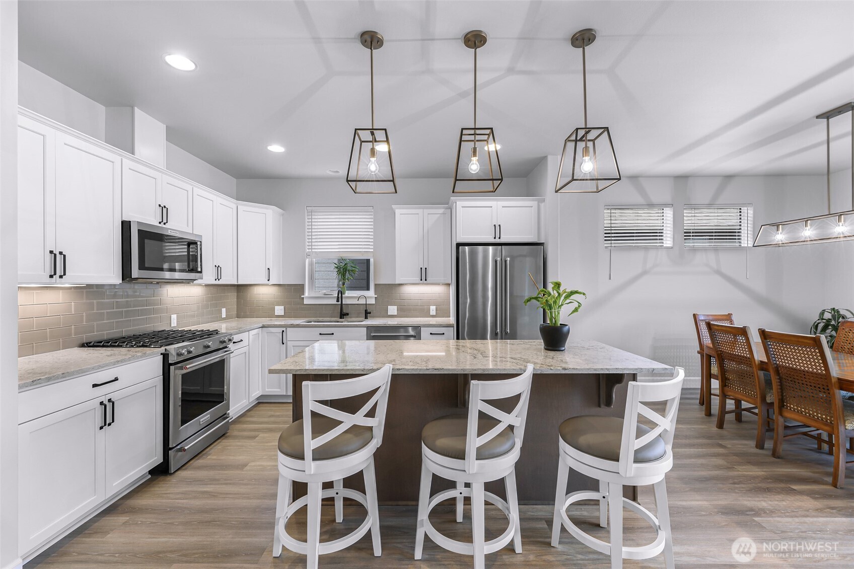 1396 Woods Point Loop Ferndale, WA 98248 - Photo 7 of 32 a kitchen with stainless steel appliances kitchen island granite countertop a sink a stove a dining table chairs and white cabinets