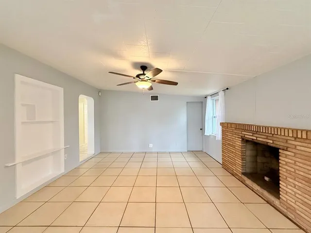 a view of an empty room and chandelier fan