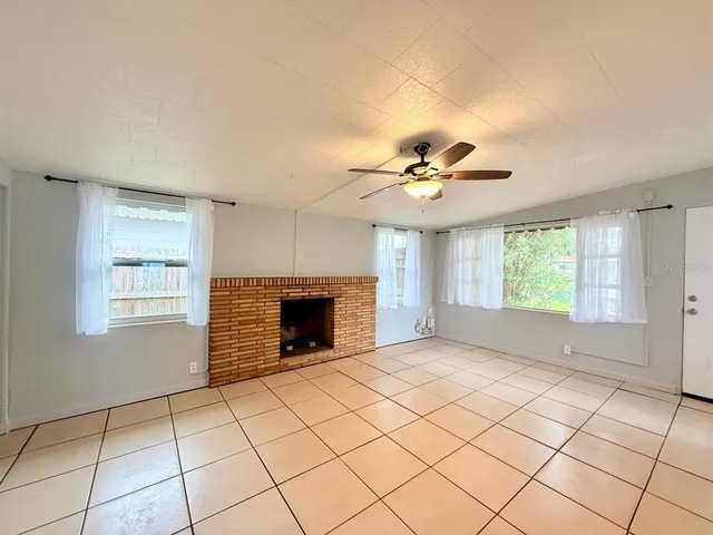 a view of an empty room with window and chandelier fan