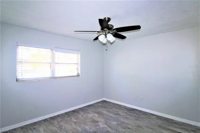 an empty room with a window and a fan