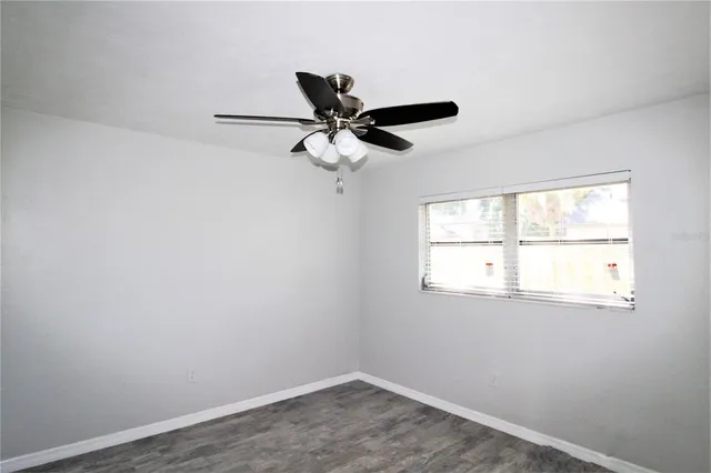 an empty room with a window and a fan