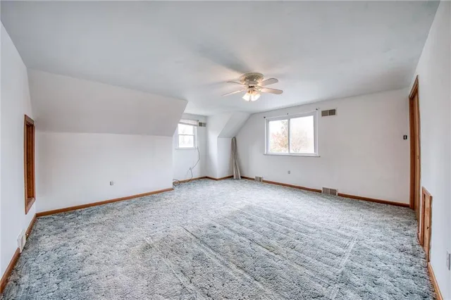 an empty room with windows and ceiling fan