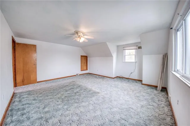 an empty room with windows and chandelier fan