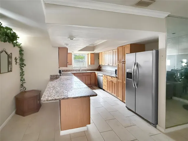a kitchen with stainless steel appliances granite countertop a sink a refrigerator and a granite counter tops