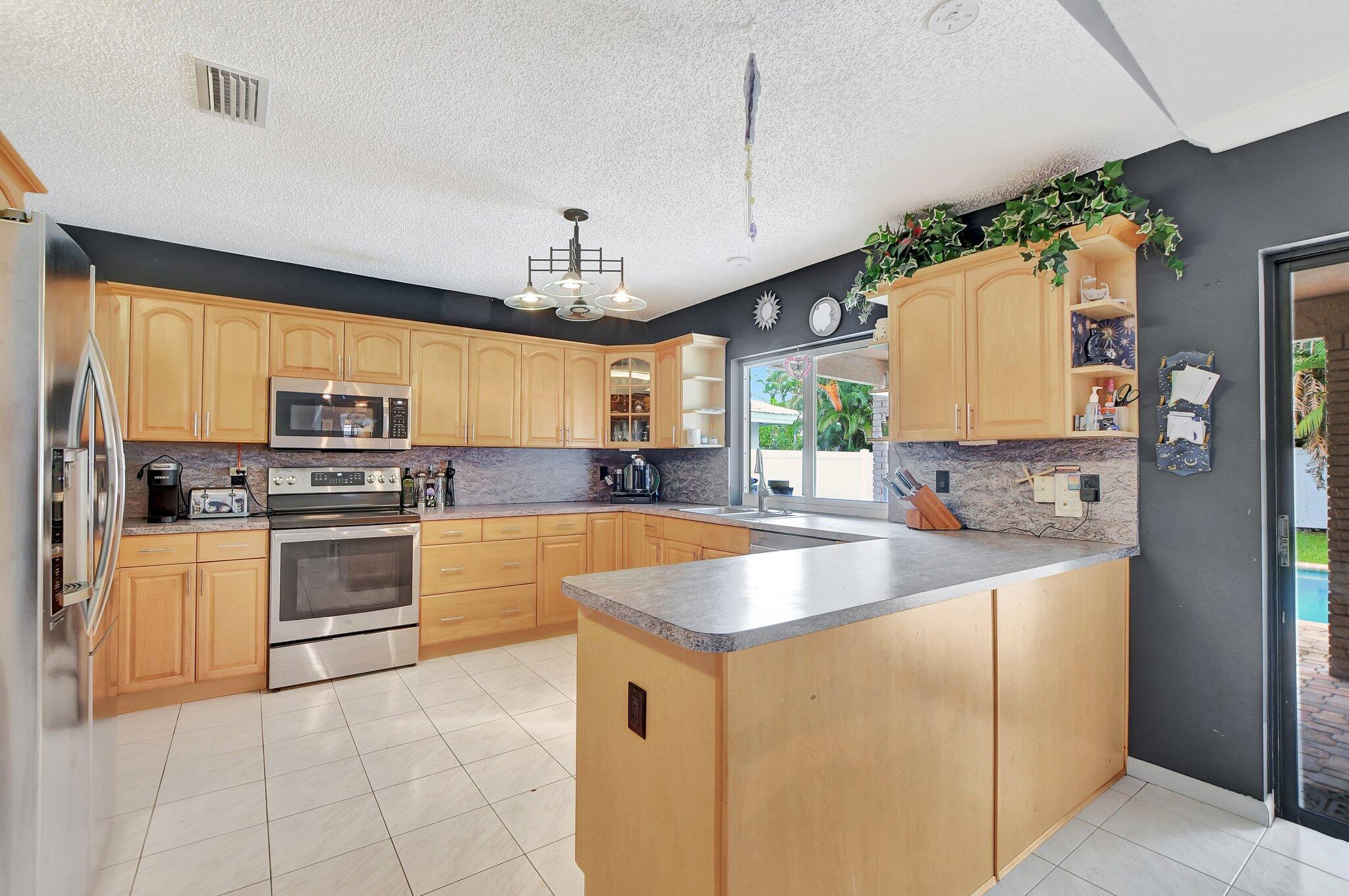 1398 Southwest 17th Street Boca Raton, FL 33486 - Photo 9 of 41 a kitchen with stainless steel appliances granite countertop a sink and dishwasher a stove top oven with wooden floor
