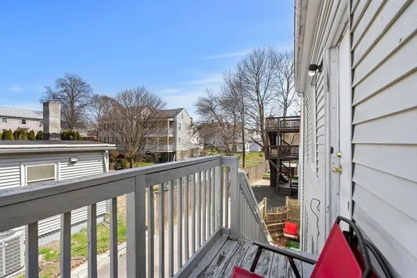 a balcony view with couple of cars parked on road in front of house