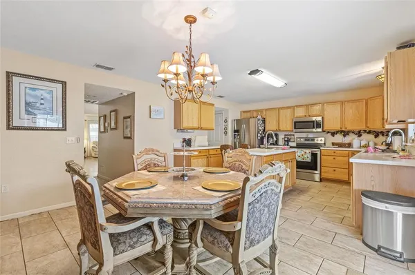 a view of a dining room and livingroom with furniture a chandelier and kitchen view