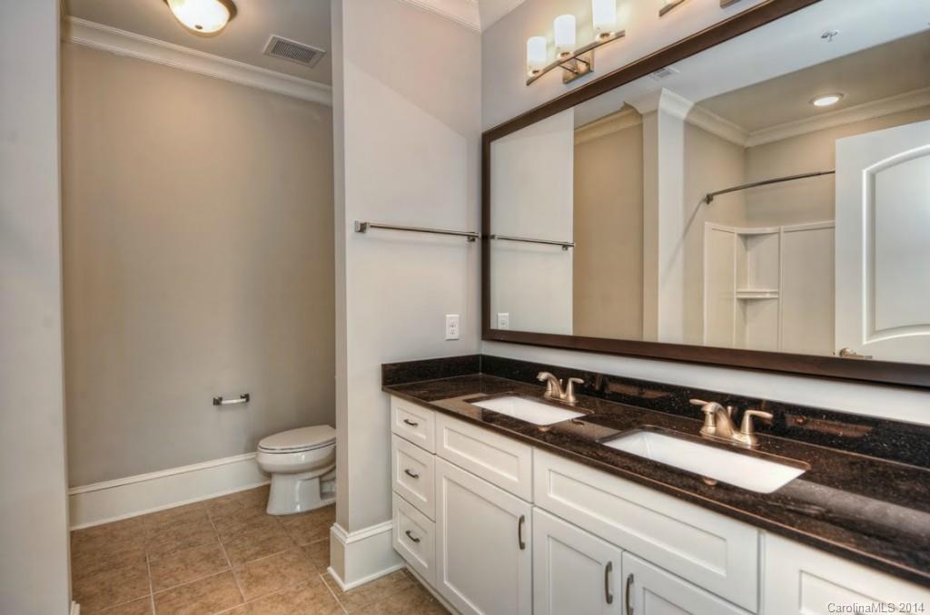 2128 Queens Road West, Unit 2128 Charlotte, NC 28209 - Photo 5 of 21 a bathroom with a granite countertop sink a toilet and a mirror