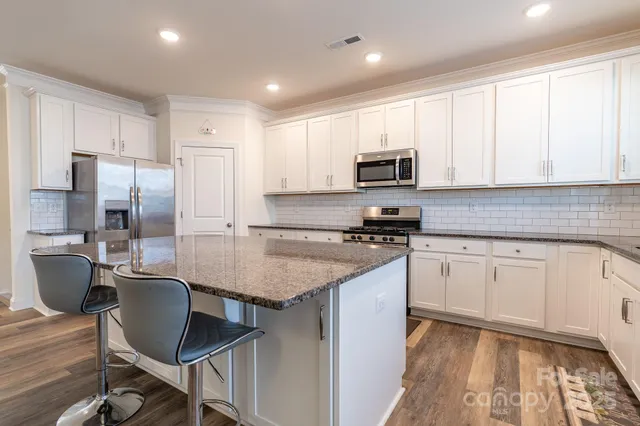 a kitchen with kitchen island granite countertop a sink cabinets and stainless steel appliances