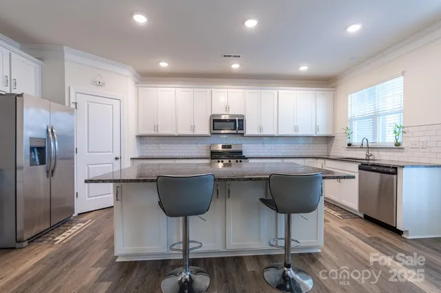 a kitchen with granite countertop a stove a sink a counter space and cabinets