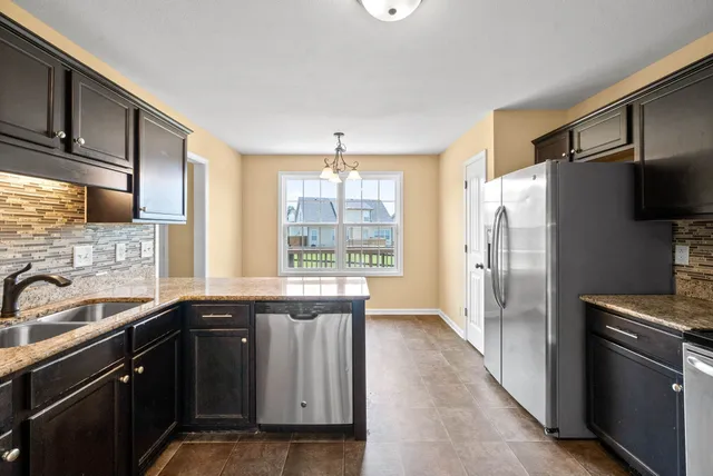 a kitchen with stainless steel appliances granite countertop a refrigerator and a sink