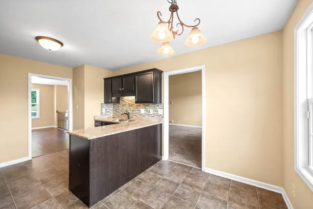 a kitchen with kitchen island granite countertop a sink and refrigerator