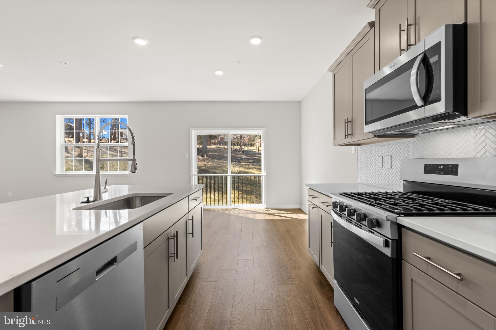 562 Atkinson Street Charles Town, WV 25414 - Photo 11 of 33 a kitchen with stainless steel appliances granite countertop a sink a stove a microwave and wooden cabinets