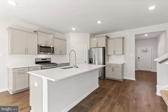 a kitchen with a sink a stove a refrigerator cabinets and a wooden floor