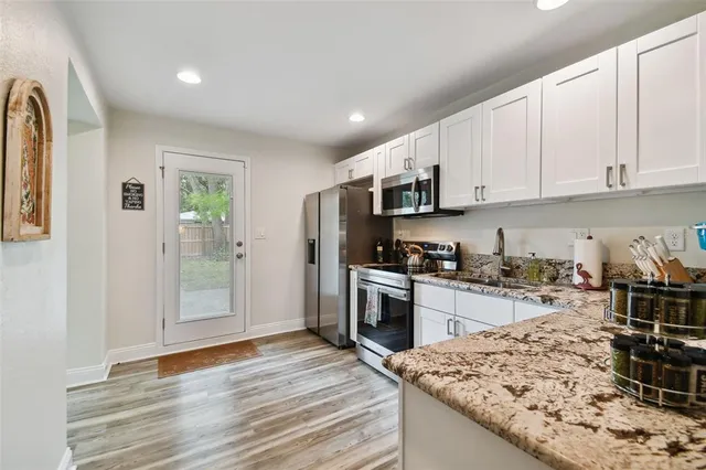 a kitchen with granite countertop a stove top oven a sink a counter space and cabinets