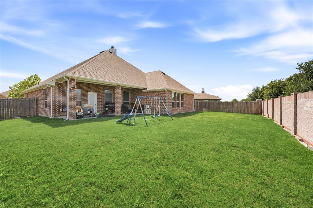 140 Chestnut Road Waxahachie, TX 75165 - Photo 25 of 26 Expansive backyard featuring a manicured lawn, brick exterior, covered patio, and a combination of wood and brick fencing