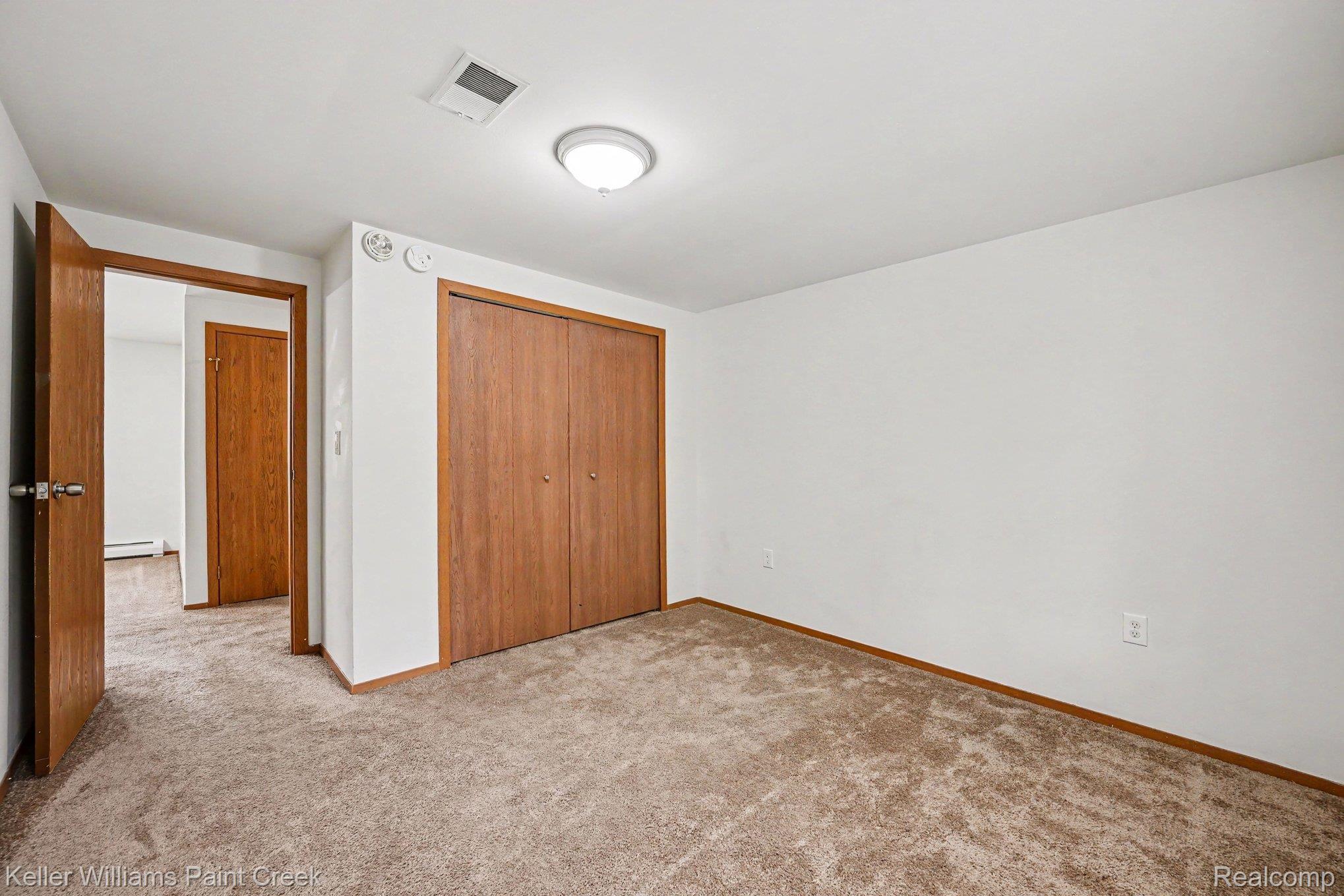 2232 London Bridge Drive Rochester, MI 48307 - Photo 20 of 26 Neutral-toned carpet flooring, a ceiling-mounted light fixture, and a built-in closet with wood-finish bi-fold doors