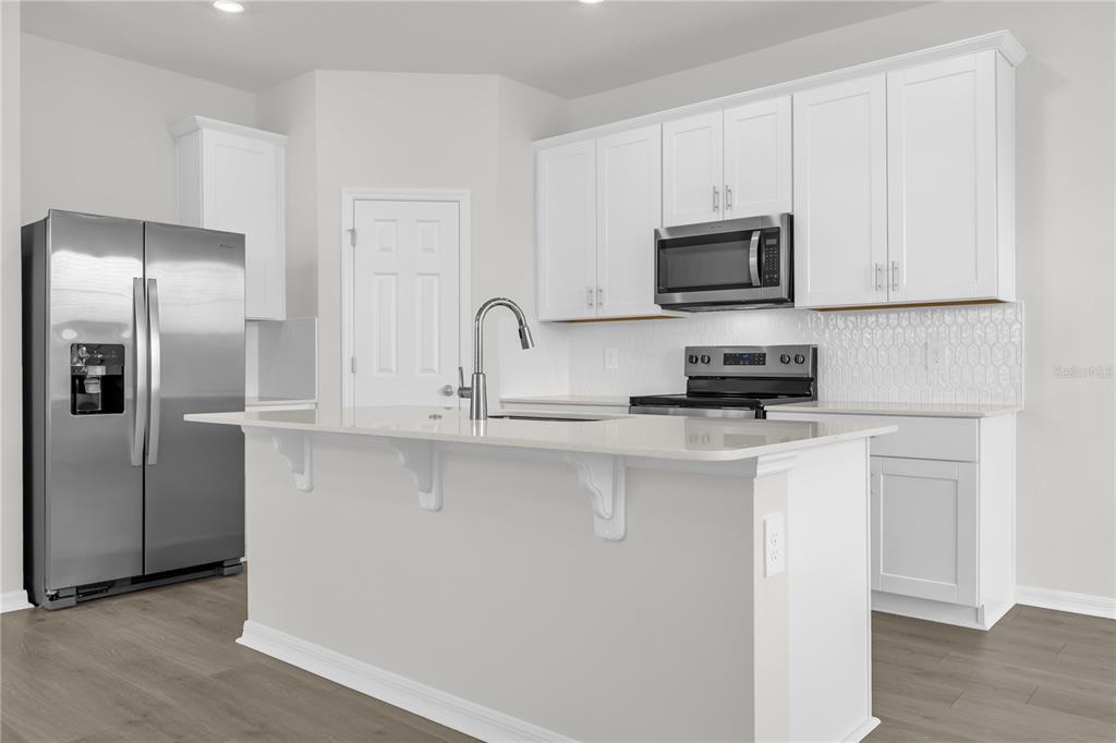 4556 Homestead Trail St. Cloud, FL 34772 - Photo 4 of 31 a kitchen with stainless steel appliances granite countertop a refrigerator a sink a stove a microwave and wooden cabinets