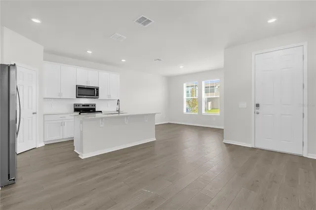 a view of an empty room with window and wooden floor