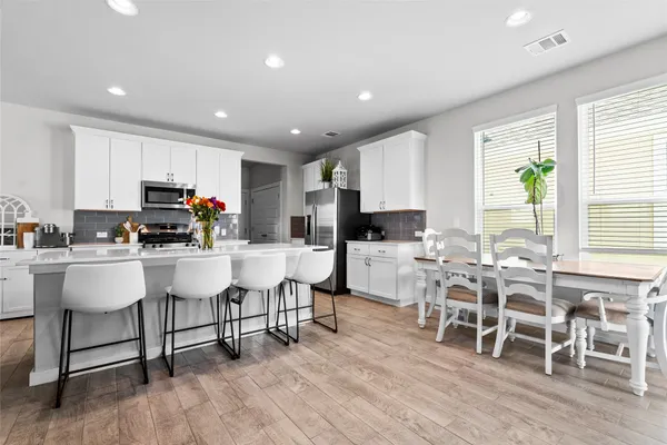 a kitchen with stainless steel appliances a dining table chairs and a refrigerator