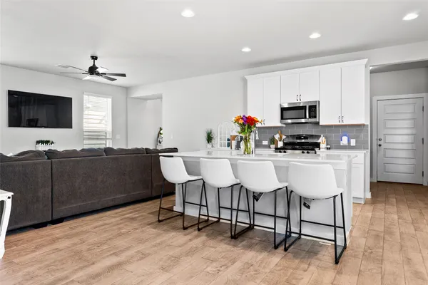a living room with furniture a flat screen tv and kitchen view