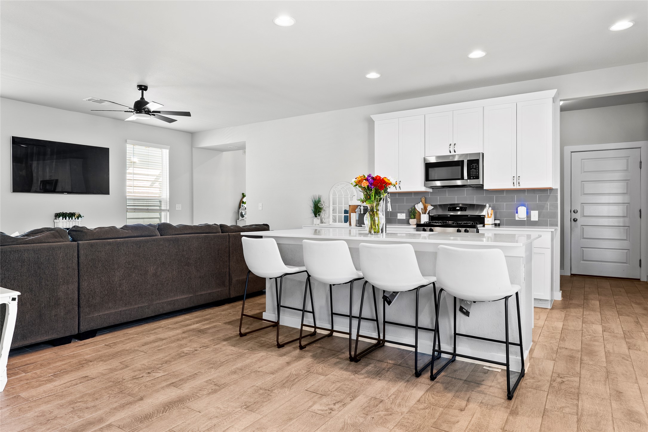 156 Appleberry Lane Elgin, TX 78621 - Photo 6 of 40 Kitchen with a breakfast bar area, an island with sink, backsplash, white cabinets, and light wood-type flooring
