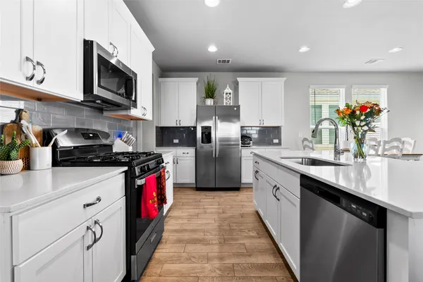 a kitchen with stainless steel appliances granite countertop a sink a stove top oven a counter space and cabinets