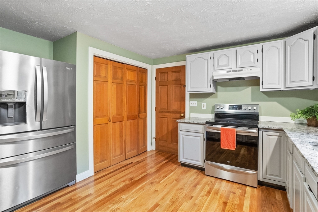 93 Turner Road Townsend, MA 01469 - Photo 9 of 32 a kitchen with granite countertop a refrigerator stove and wooden floor