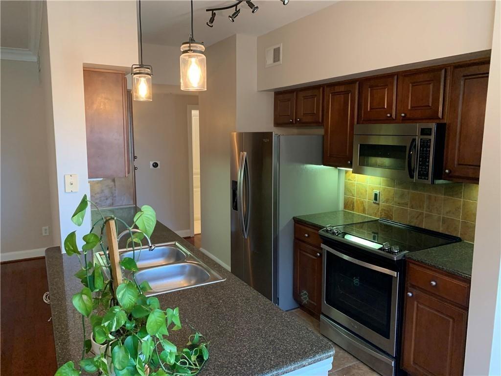 7701 Rialto Boulevard, Unit 1222 Austin, TX 78735 - Photo 2 of 14 A streamlined kitchen provides efficient cooking and abundant storage with rich wood cabinetry.