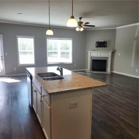 a kitchen with granite countertop a stove two sinks a window and wooden floor