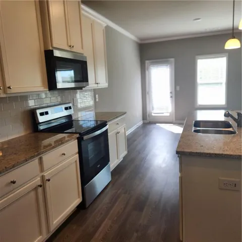 a kitchen with stainless steel appliances granite countertop a stove a sink dishwasher and a microwave oven with wooden floor