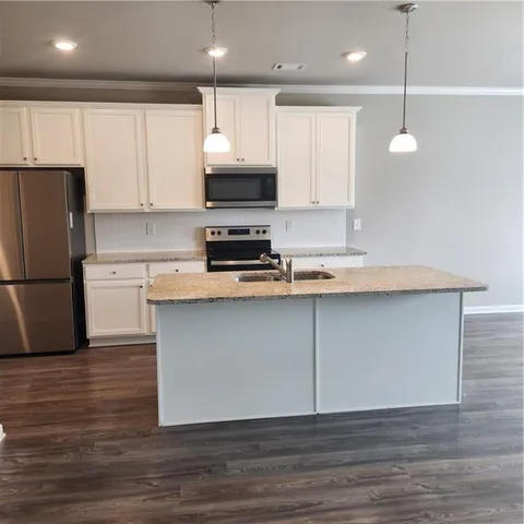 a kitchen with stainless steel appliances granite countertop a sink a stove a refrigerator and white cabinets