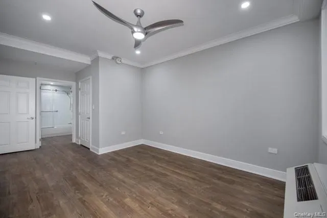 an empty room with wooden floor and ceiling fan