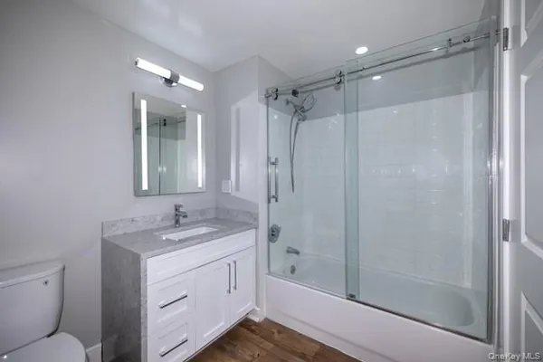 a bathroom with a shower sink vanity mirror and toilet