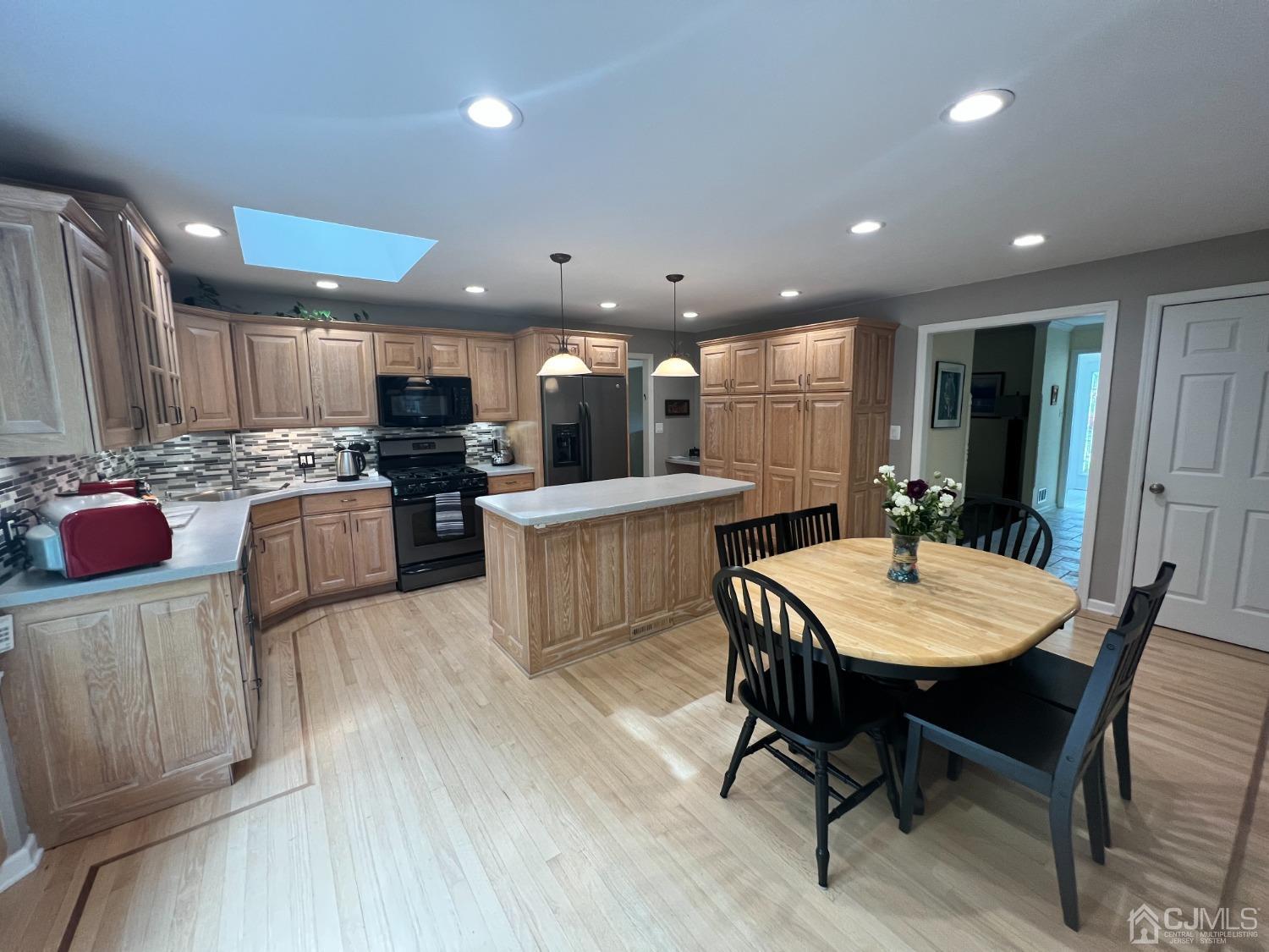 55 Winton Road East Brunswick, NJ 08816 - Photo 3 of 39 a kitchen with stainless steel appliances kitchen island granite countertop a dining table chairs refrigerator sink and cabinets