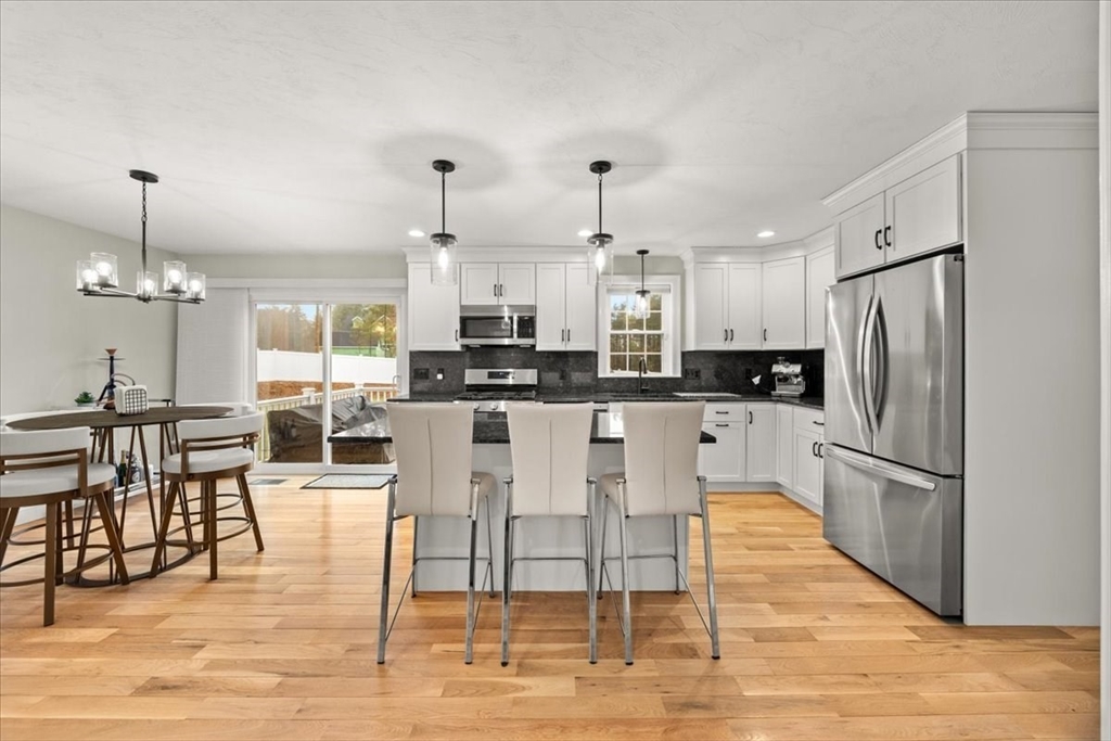 70 Sandy Hill Road Raynham, MA 02767 - Photo 14 of 42 a kitchen with stainless steel appliances a dining table chairs stove and refrigerator