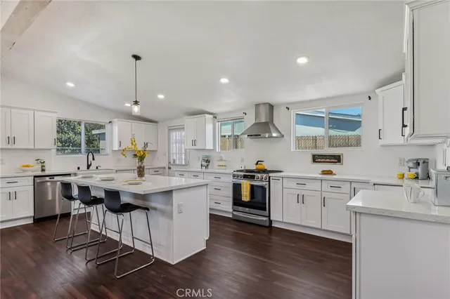 a kitchen with stainless steel appliances granite countertop a sink stove and white cabinets with wooden floor