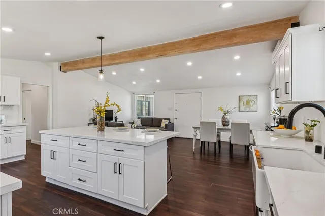 a kitchen with stainless steel appliances granite countertop a sink a stove a dining table chairs and view living room