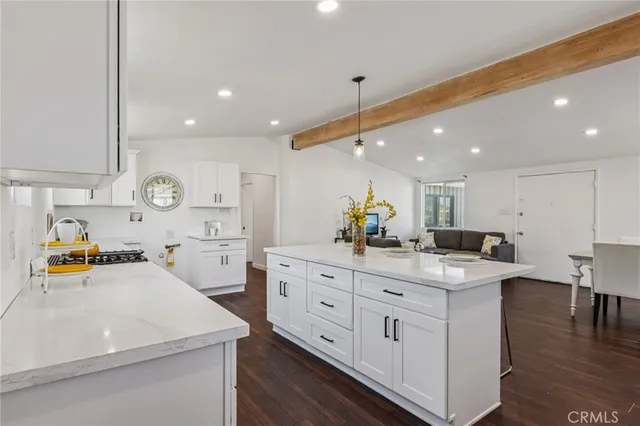 a kitchen with stainless steel appliances kitchen island granite countertop a sink and white cabinets with wooden floor