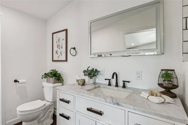 a bathroom with a granite countertop sink a toilet and a mirror