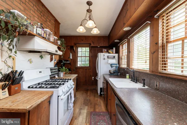 a kitchen with stainless steel appliances granite countertop a sink a stove and a wooden floors
