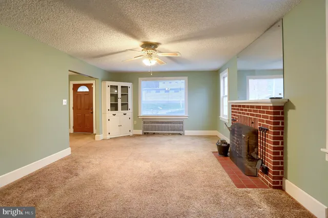 a view of an empty room with window and chandelier fan