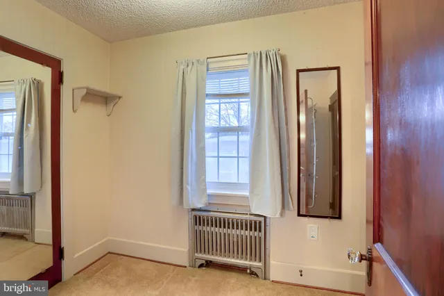 an empty room with chandelier fan and windows