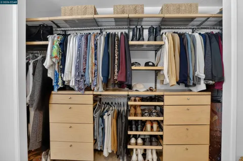 a view of walk in closet with clothes and shoes
