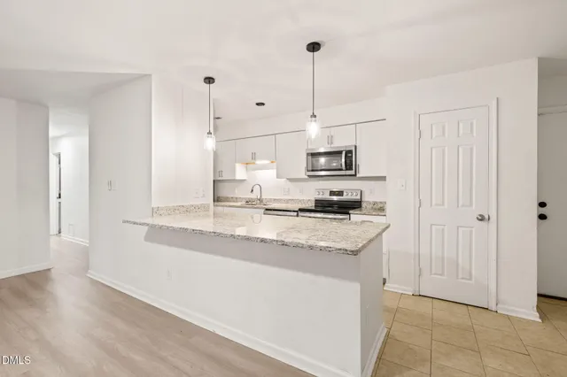 a kitchen with stainless steel appliances kitchen island granite countertop a sink a stove and a wooden floors